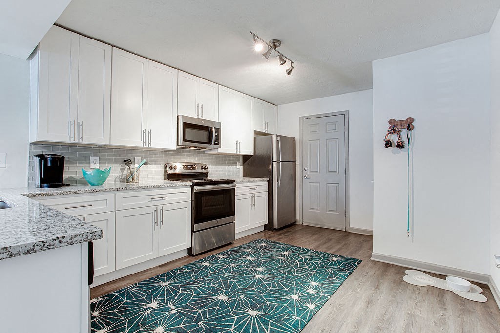 a kitchen with white cabinets and a stainless steel refrigerator