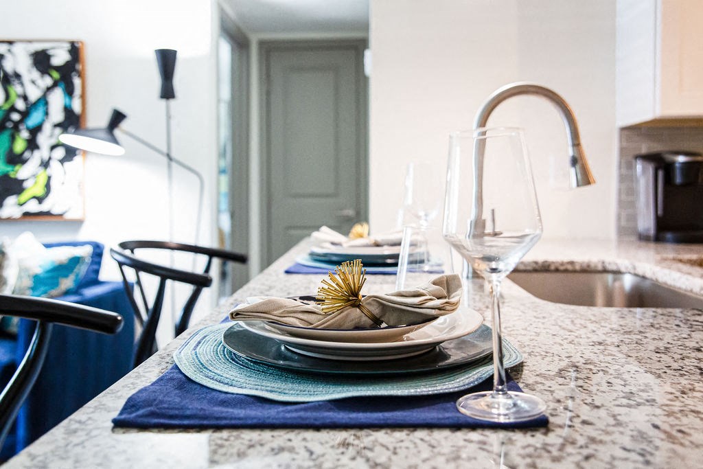 a kitchen counter with plates and wine glasses on it