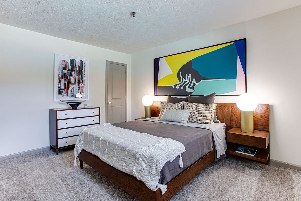 a bedroom with a bed and a painting on the wall