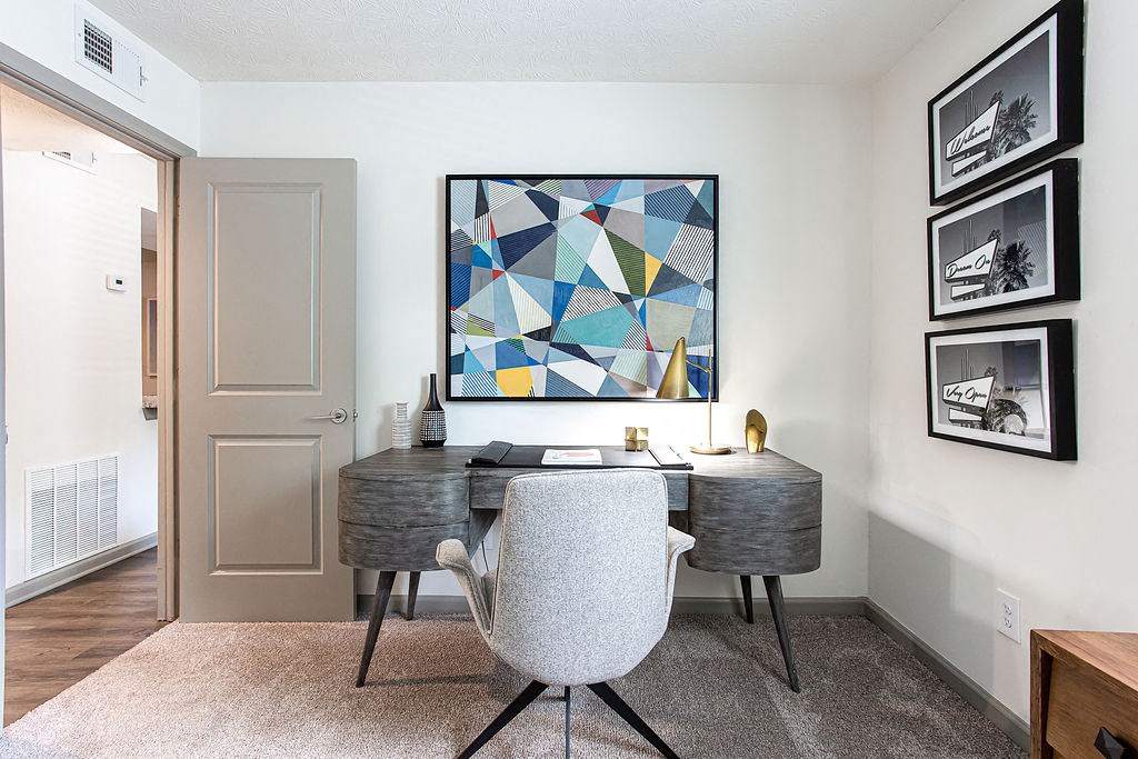 a home office with a desk and chair and a painting on the wall