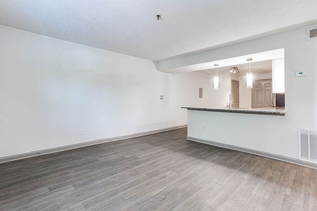 the living room and kitchen of an empty apartment with wood flooring