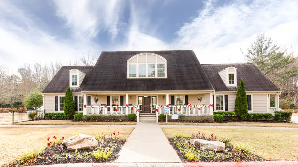 a house with a black roof and a white fence with red flags on it
