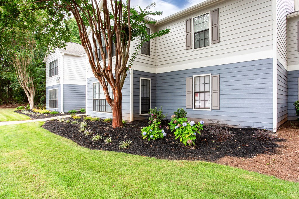 a front yard with a tree and some plants in front of a house at Magnolia Place at Stockbridge Apartments, Stockbridge, GA, 30281