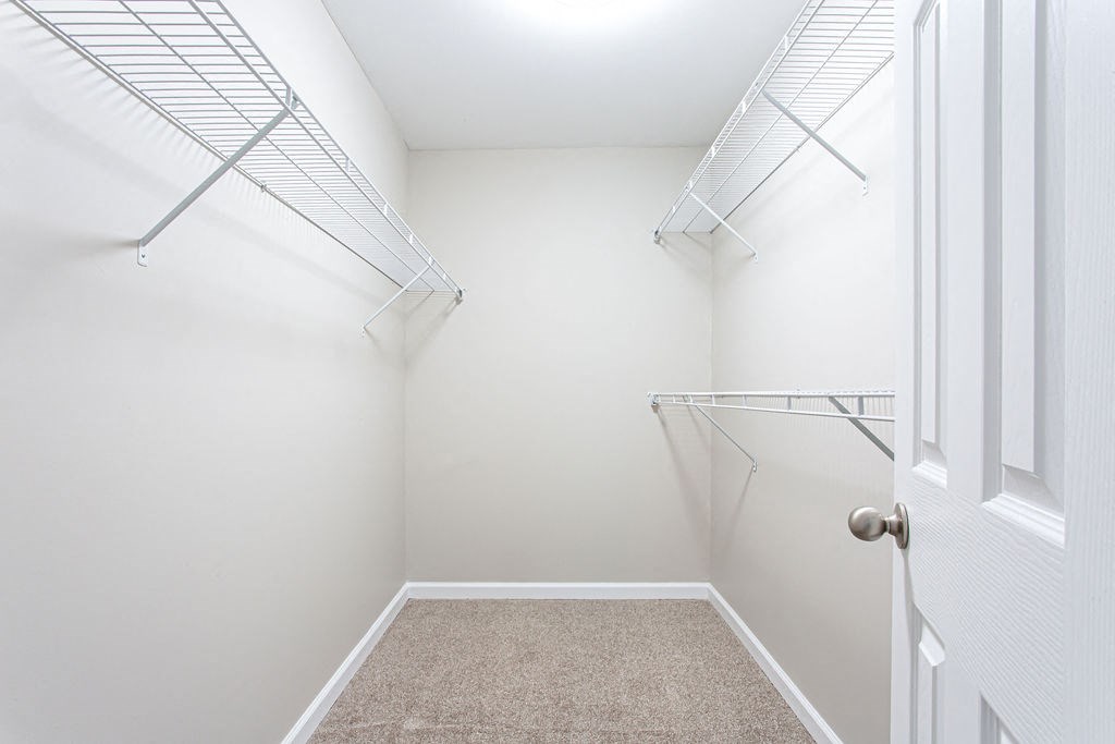 a walk in closet in a home with white walls and a white door at Magnolia Place at Stockbridge Apartments, Stockbridge, Georgia