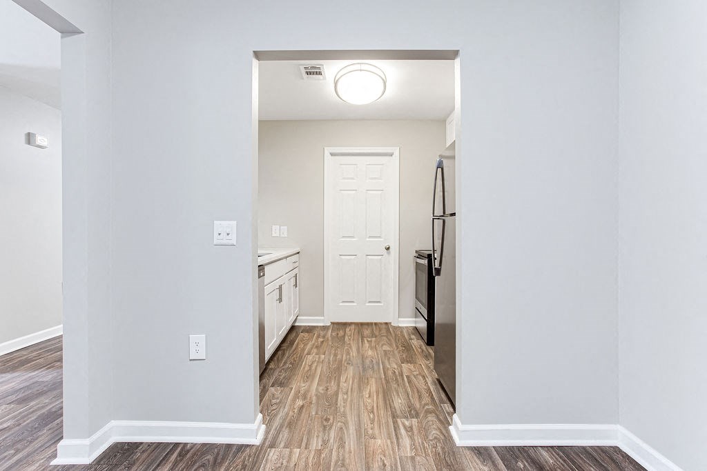 a renovated living room and kitchen with white walls and wood floors at Magnolia Place at Stockbridge Apartments, Stockbridge, GA