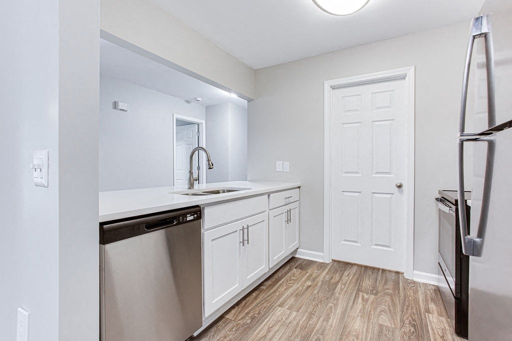 a renovated kitchen with white cabinets and a stainless steel refrigerator at Magnolia Place at Stockbridge Apartments, Georgia, 30281