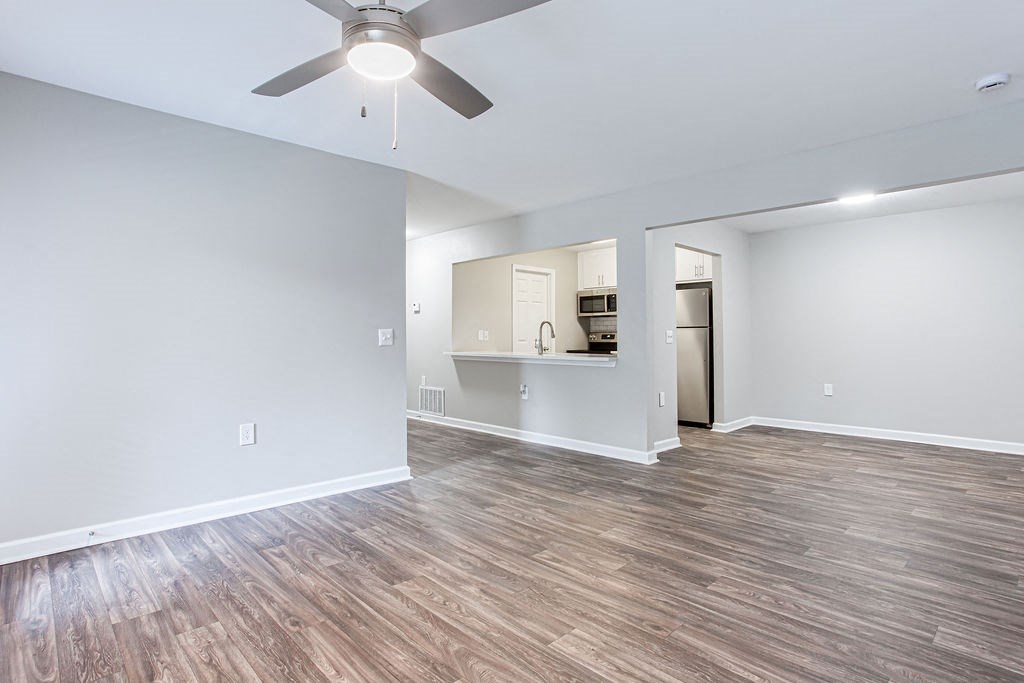 an empty living room with a ceiling fan and a kitchen at Magnolia Place at Stockbridge Apartments, Georgia