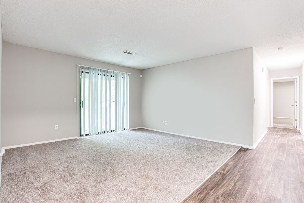 an empty living room with a sliding glass door at Magnolia Place at Stockbridge Apartments, Stockbridge, GA