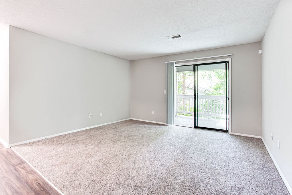 an empty living room with a door to a balcony at Magnolia Place at Stockbridge Apartments, Stockbridge, 30281
