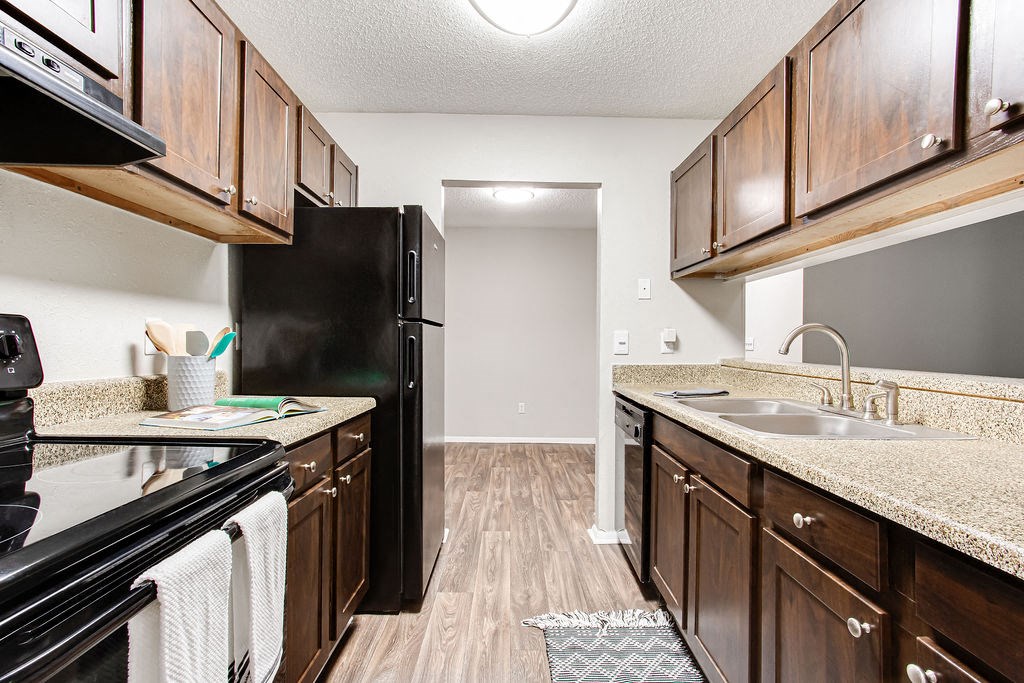a kitchen with black appliances and wooden cabinets at Magnolia Place at Stockbridge Apartments, Georgia, 30281
