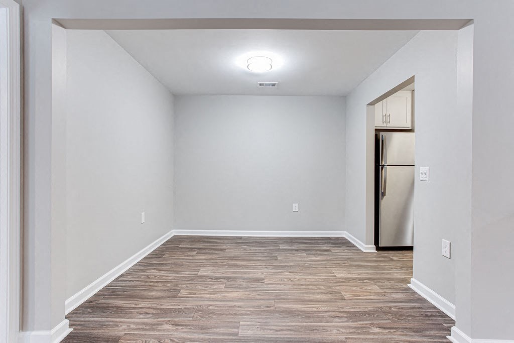 Dining room with white walls and wood flooring and a refrigerator at Magnolia Place at Stockbridge Apartments, Stockbridge