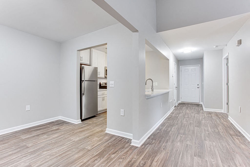 a renovated living room with a kitchen with a stainless steel refrigerator at Magnolia Place at Stockbridge Apartments, Stockbridge