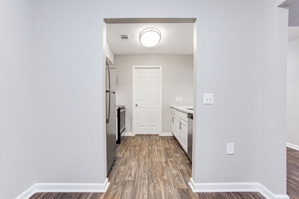 a renovated living room and kitchen with white walls and wood floors at Magnolia Place at Stockbridge Apartments, Stockbridge, GA, 30281