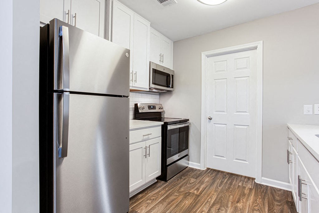 a kitchen with stainless steel appliances and white cabinets at Magnolia Place at Stockbridge Apartments, Stockbridge, Georgia