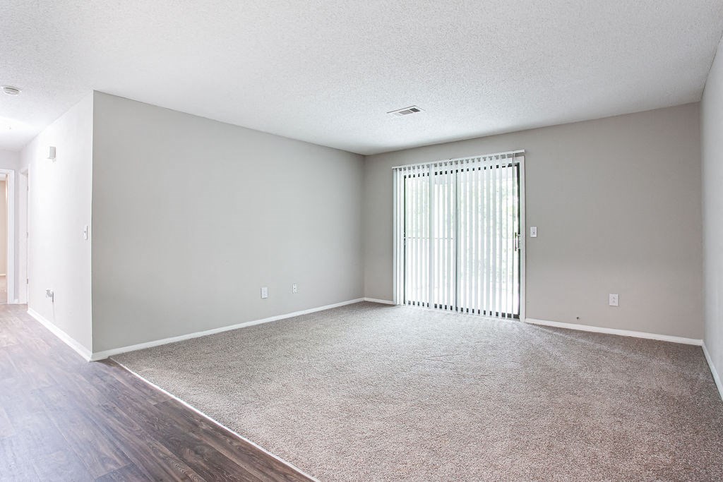 living room with sliding glass door and carpet at Magnolia Place at Stockbridge Apartments, Stockbridge