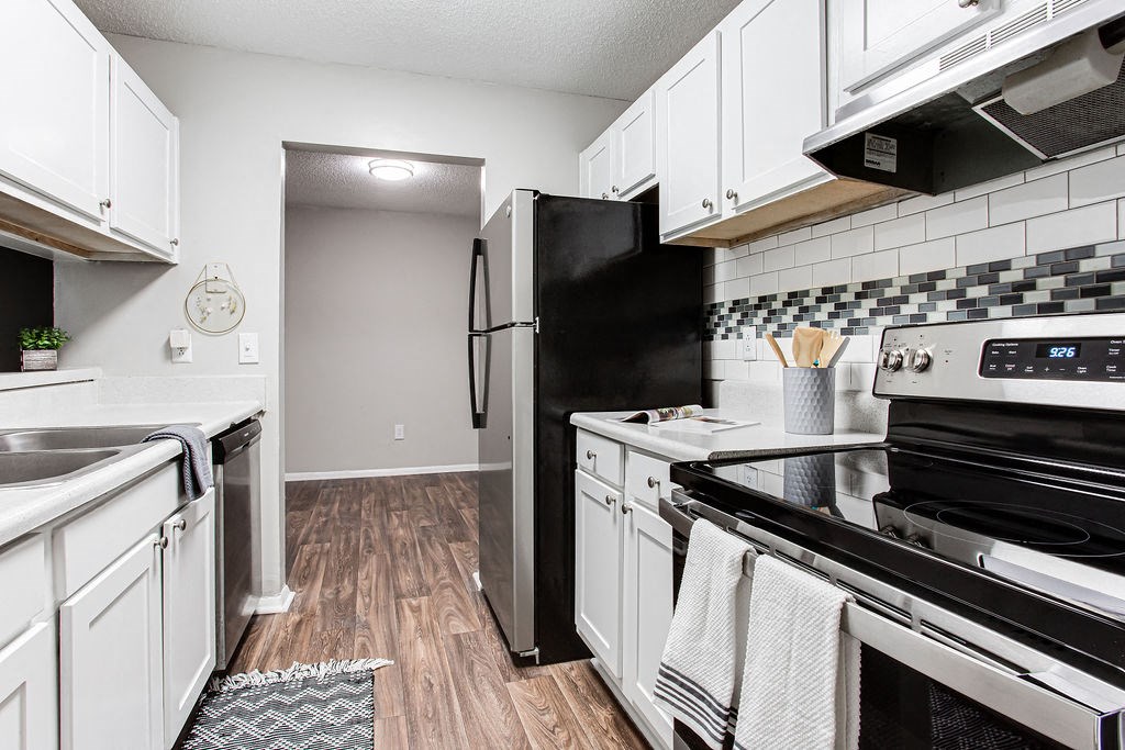 a kitchen with white cabinets and stainless appliances at Magnolia Place at Stockbridge Apartments, Georgia