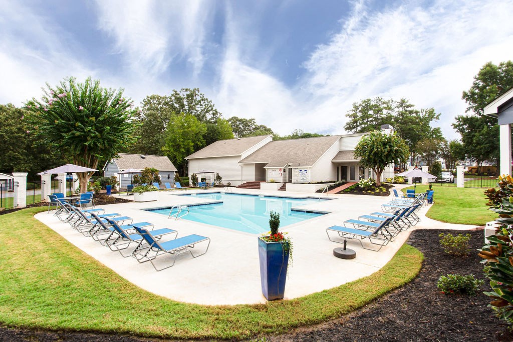 a swimming pool with lounge chairs around it in front of a house at Magnolia Place at Stockbridge Apartments, Georgia