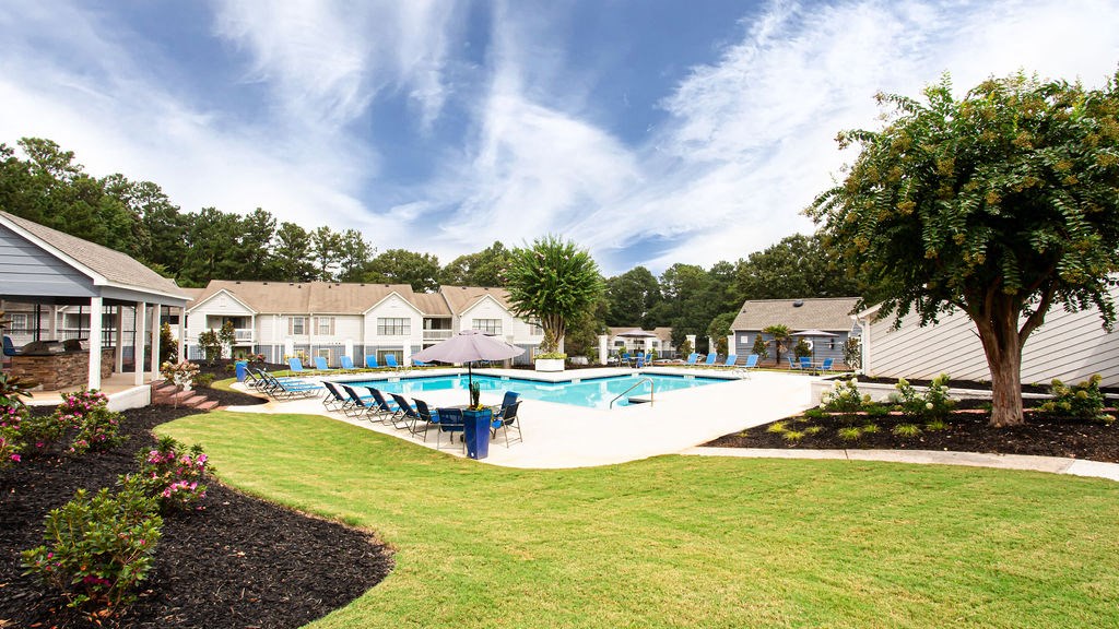 a swimming pool with a tree in the middle of a yard at Magnolia Place at Stockbridge Apartments, Stockbridge, 30281