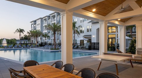 A poolside dining area with a table and chairs.