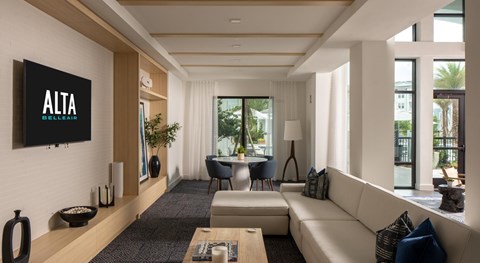 A living room with a white couch and a flat screen TV mounted on the wall.