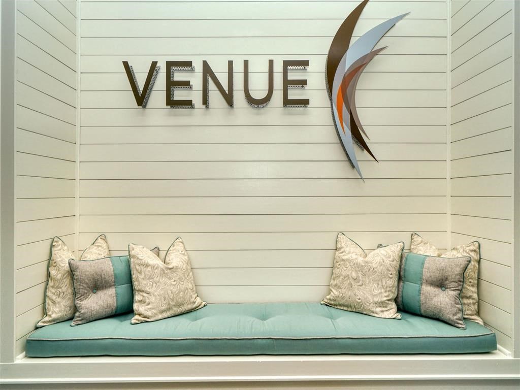 a bench with pillows under the venu logo on the wall