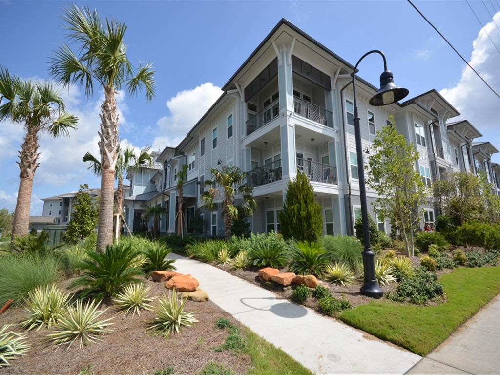 a sidewalk in front of a building with palm trees