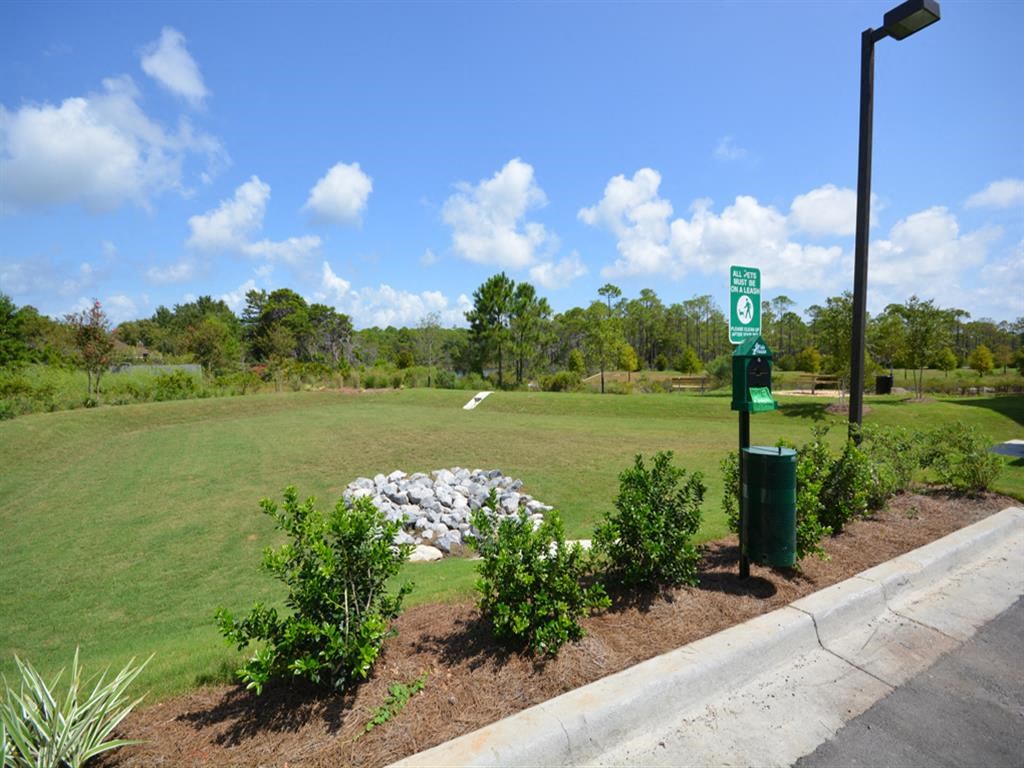 a park with a grass field and a parking sign
