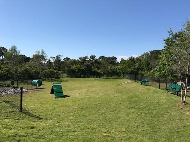 a park with a field with benches and a fence