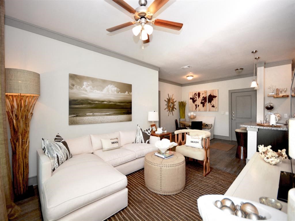 a living room with white furniture and a ceiling fan