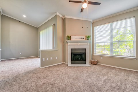 A living room with a fireplace and a ceiling fan.