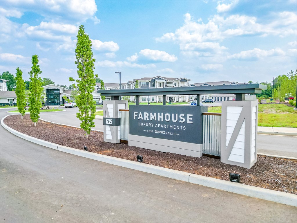 a farmhouse sign on the side of a road