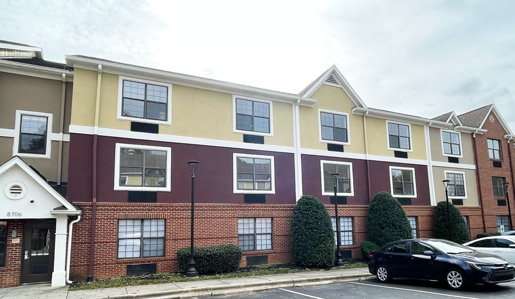 a brick apartment building with a black car parked in front