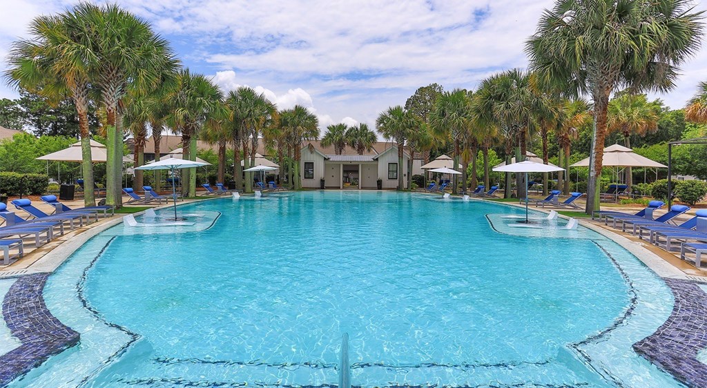 A large swimming pool surrounded by palm trees and lounge chairs.