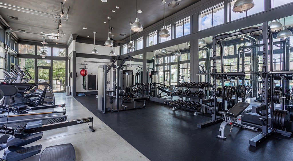 A gym with a variety of equipment including treadmills, weights, and exercise machines.