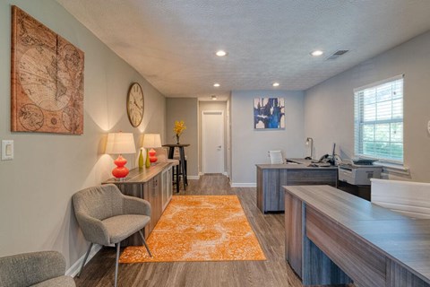 A living room with a grey chair and a brown rug.