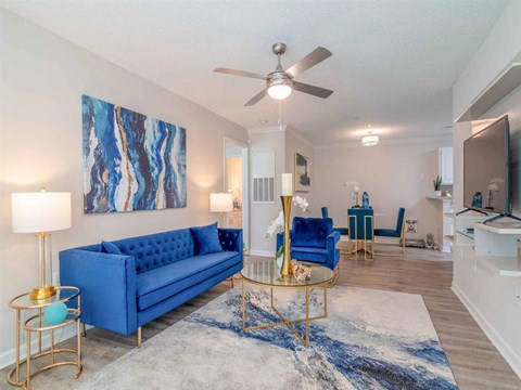 a living room with blue couches and a ceiling fan
