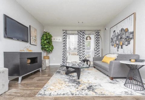 A living room with a grey couch, a black fireplace, and a large painting on the wall.