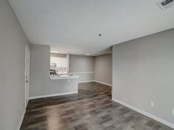 an empty living room and kitchen with a hard wood floor