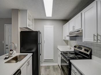 a kitchen with white cabinets and black appliances