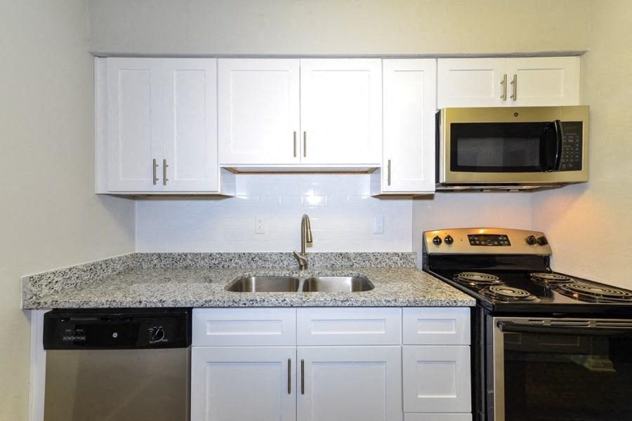a kitchen with white cabinets and a sink and a stove