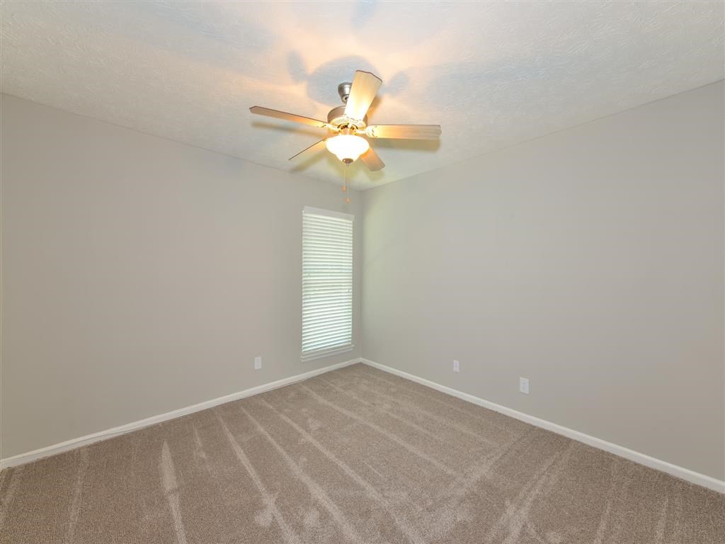 an empty room with a ceiling fan and a window
