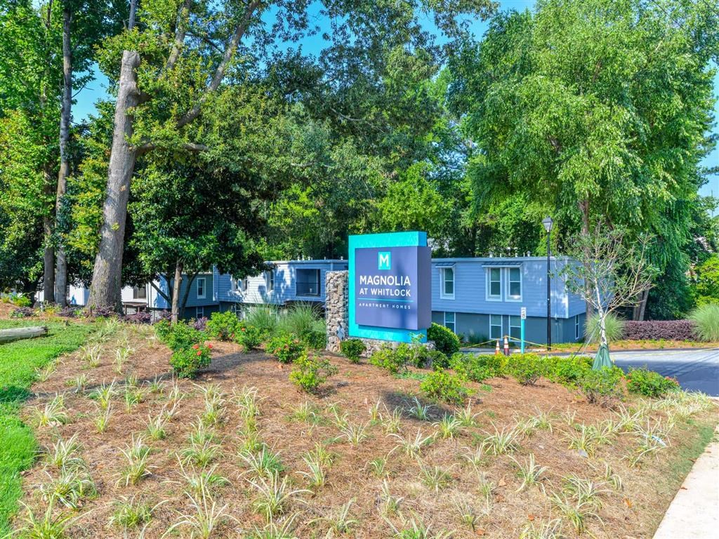 a blue building with a sign in front of trees and a road
