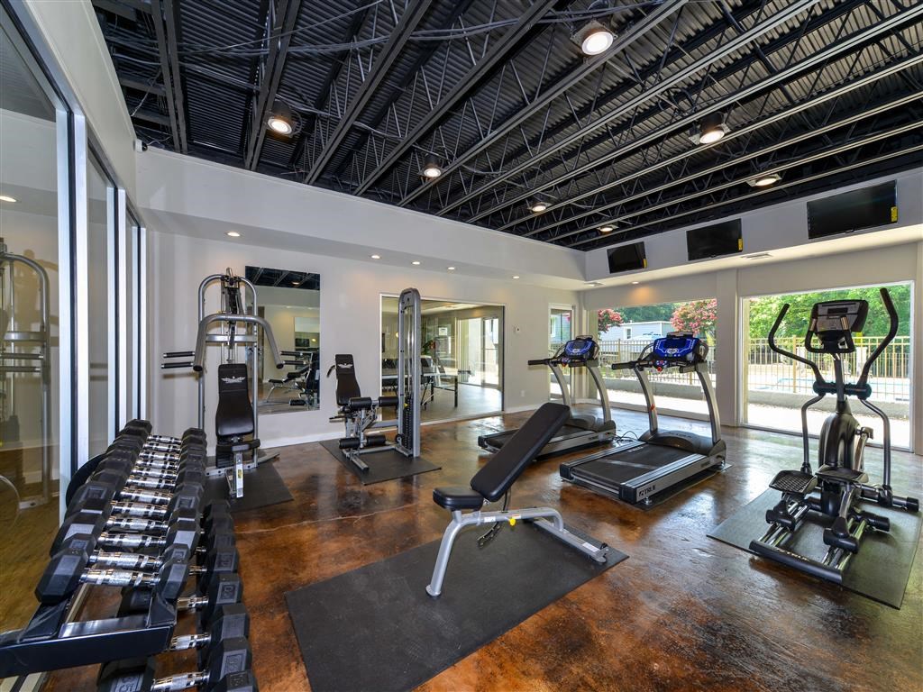 a gym with treadmills and other exercise equipment in a large room with windows