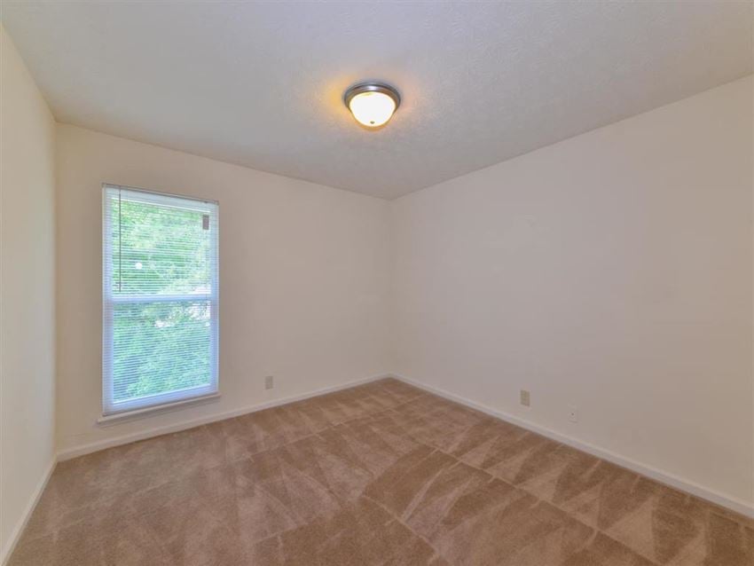 an empty living room with a window and carpet