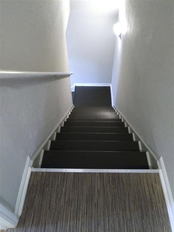 a set of stairs with black carpet and white walls