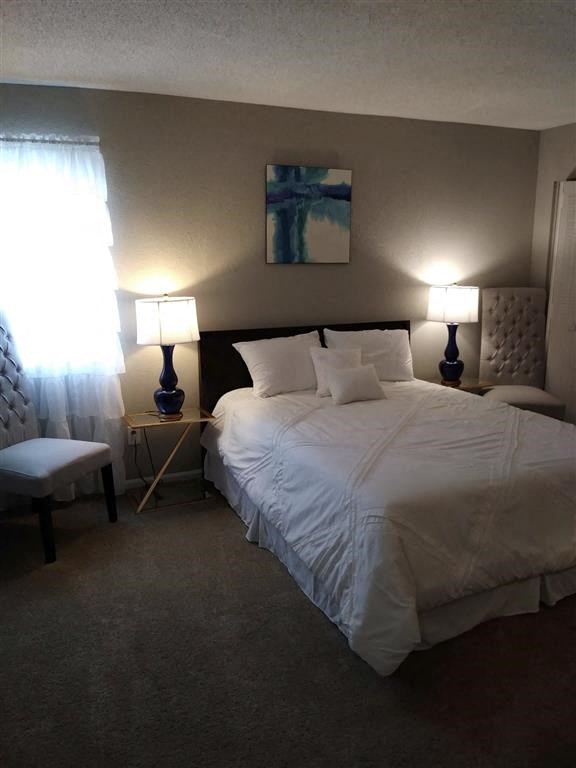 a bedroom with a bed and a chair and a window