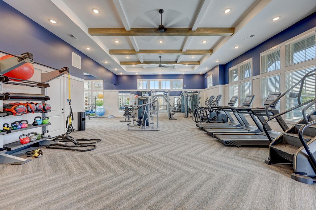 a gym with cardio machines and weights on the floor and a window at Century Mundy Mill Apartments, Oakwood