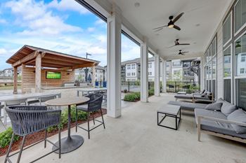 a patio with couches and tables and large windows at Century Mundy Mill Apartments, Oakwood