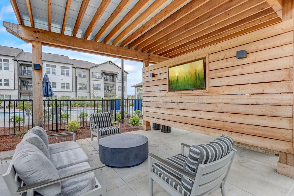 a patio with chairs and a table in front of a wooden house at Century Mundy Mill Apartments, Georgia 30566