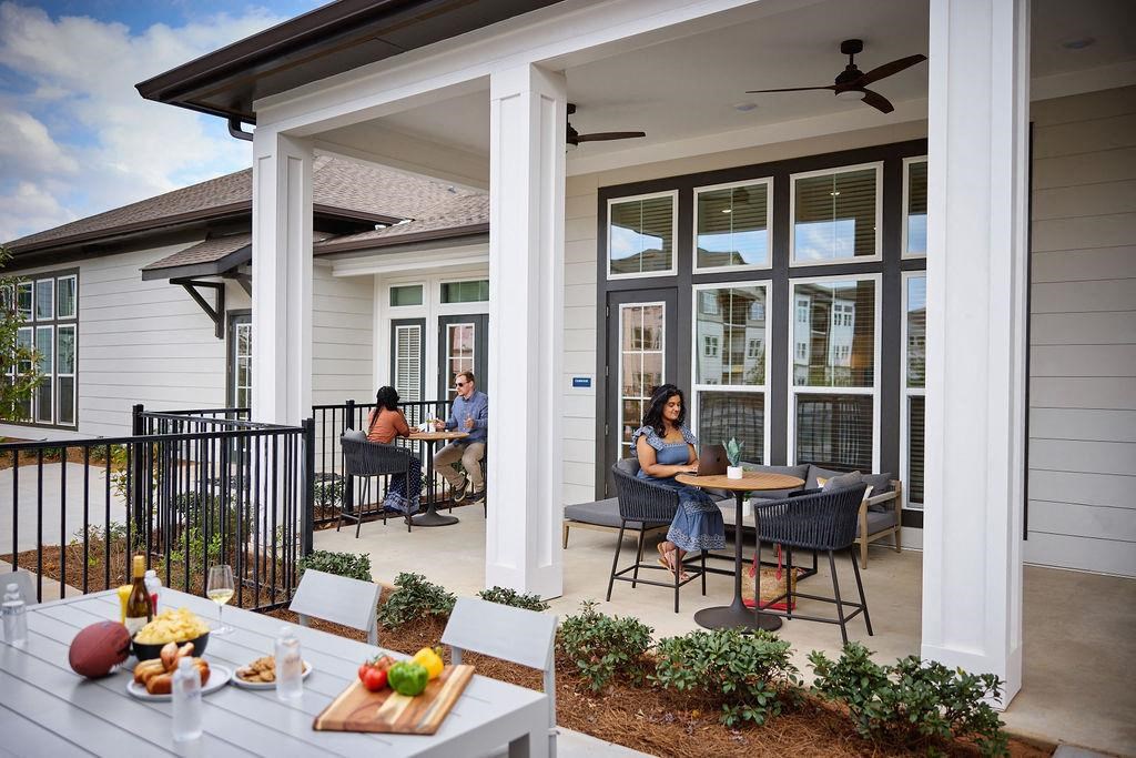 a group of people sitting at tables on a patio at Century Mundy Mill Apartments, Oakwood, GA